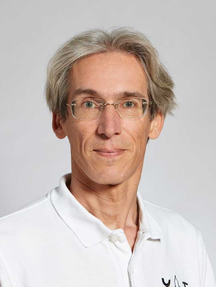 Portrait of Prof. Konrad Schindler in a white polo shirt, smiling at the camera