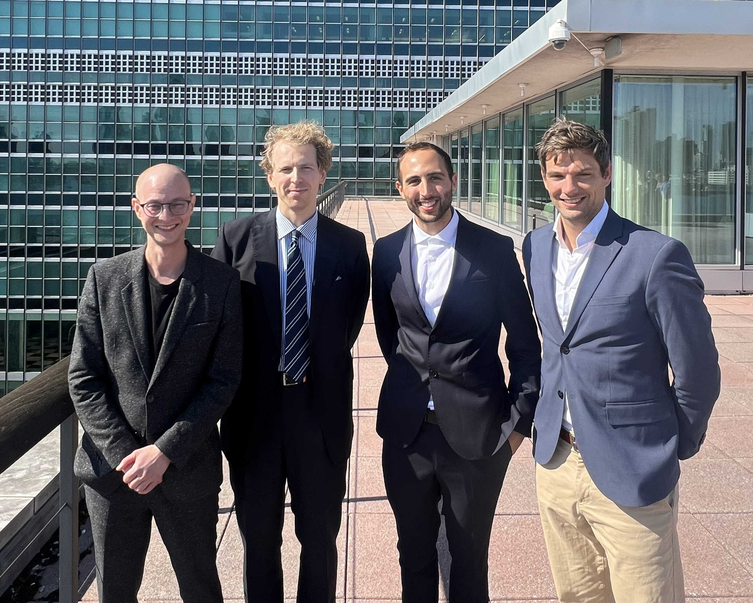 A group of four men, Dr. Sascha Langenbach, Leo Eigner, Francesco Re, and Prof. Dr. Allard Duursma, stand together in New York before presenting their project to the Permanent Mission of Switzerland to the UN.