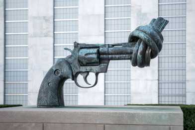 Bronze sculpture of a revolver with its barrel tied in a knot, symbolizing peace and non-violence, located in front of the UN headquarters.